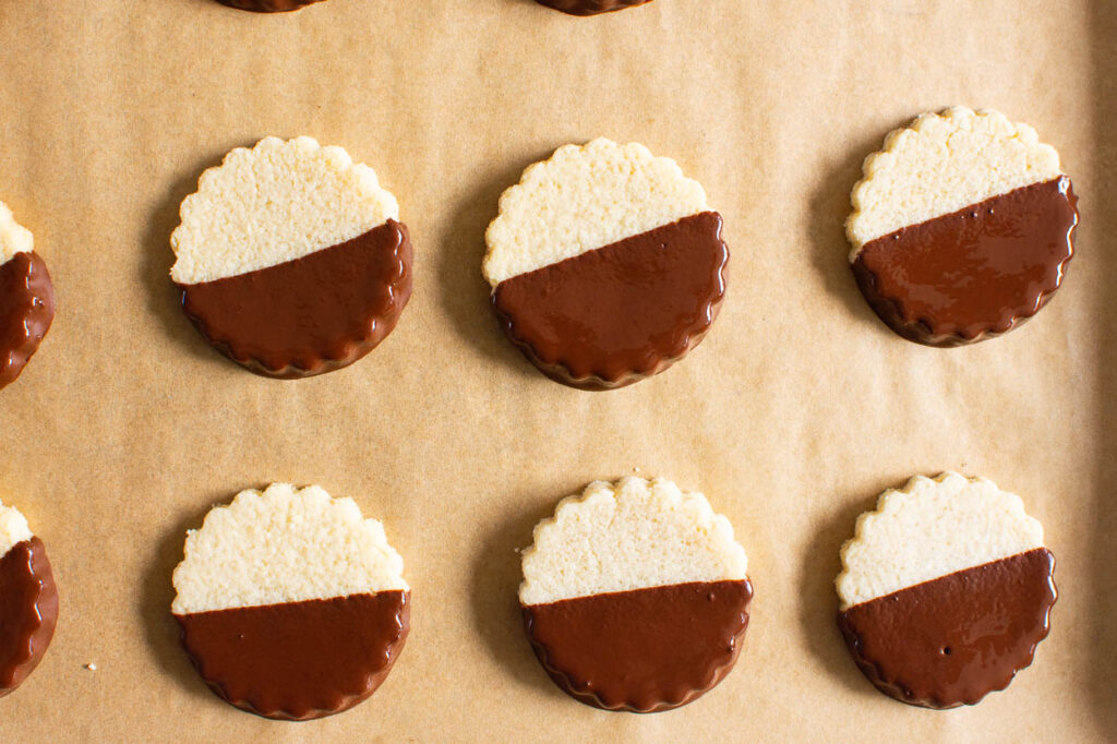 Shortbread cookies dipped in chocolate placed on parchment lined pan.