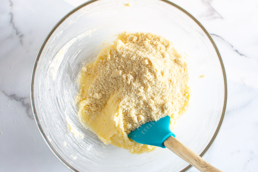 Adding almond flour to butter and sugar mixture.