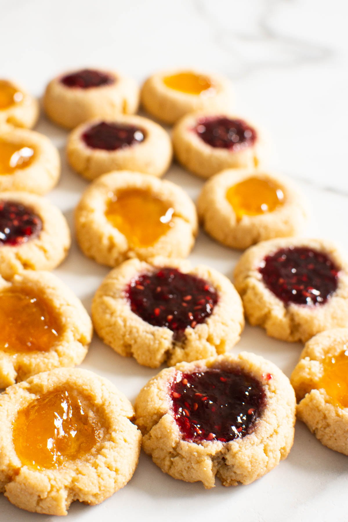 Almond flour thumbprint cookies filled with jam on surface.