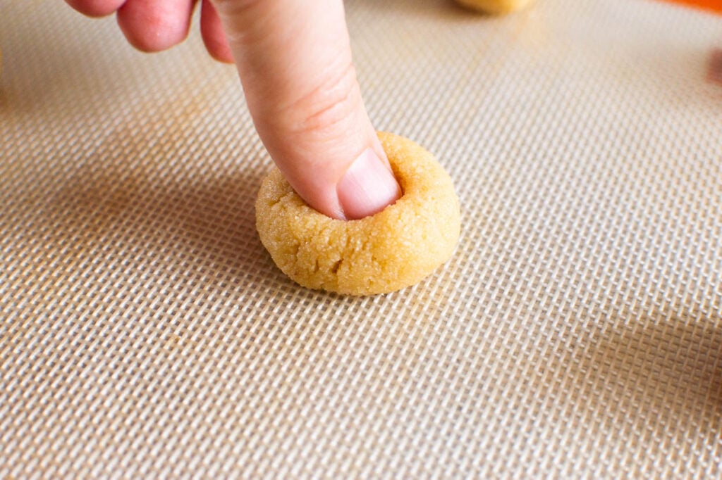 Making indent in cookie dough with finger. 