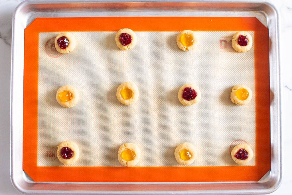 Cookies filled with jam on silpat baking pan.