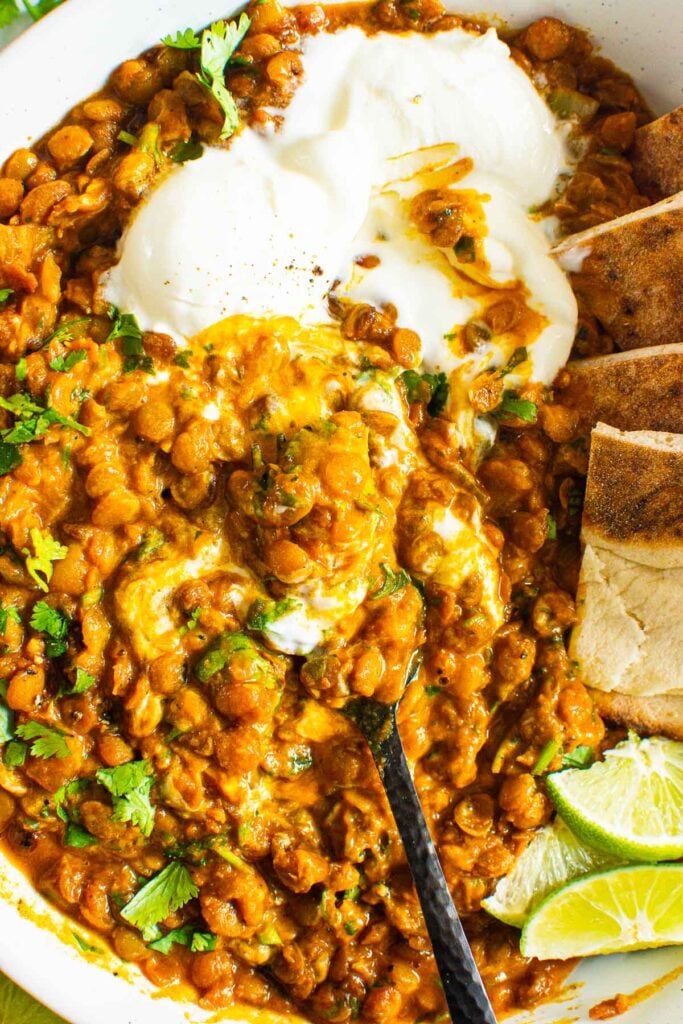 close up of coconut lentil recipe with a dollop of yogurt and pita bread