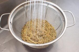 dried lentils being rinsed in a colander