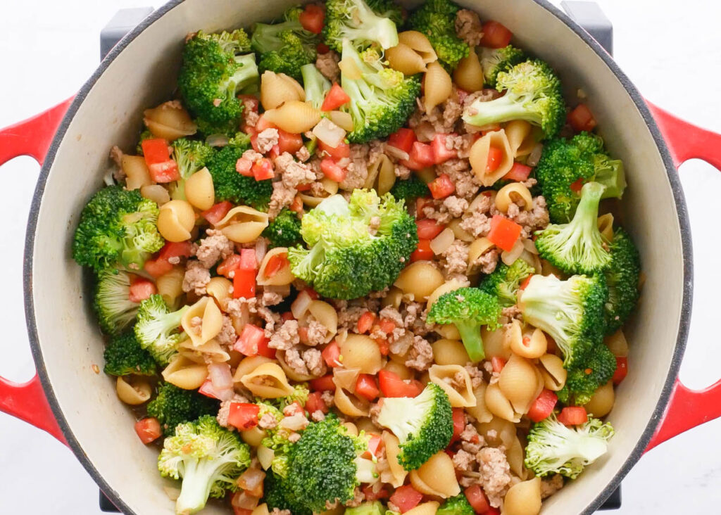 Pot with broccoli, shell pasta, ground turkey and tomatoes.