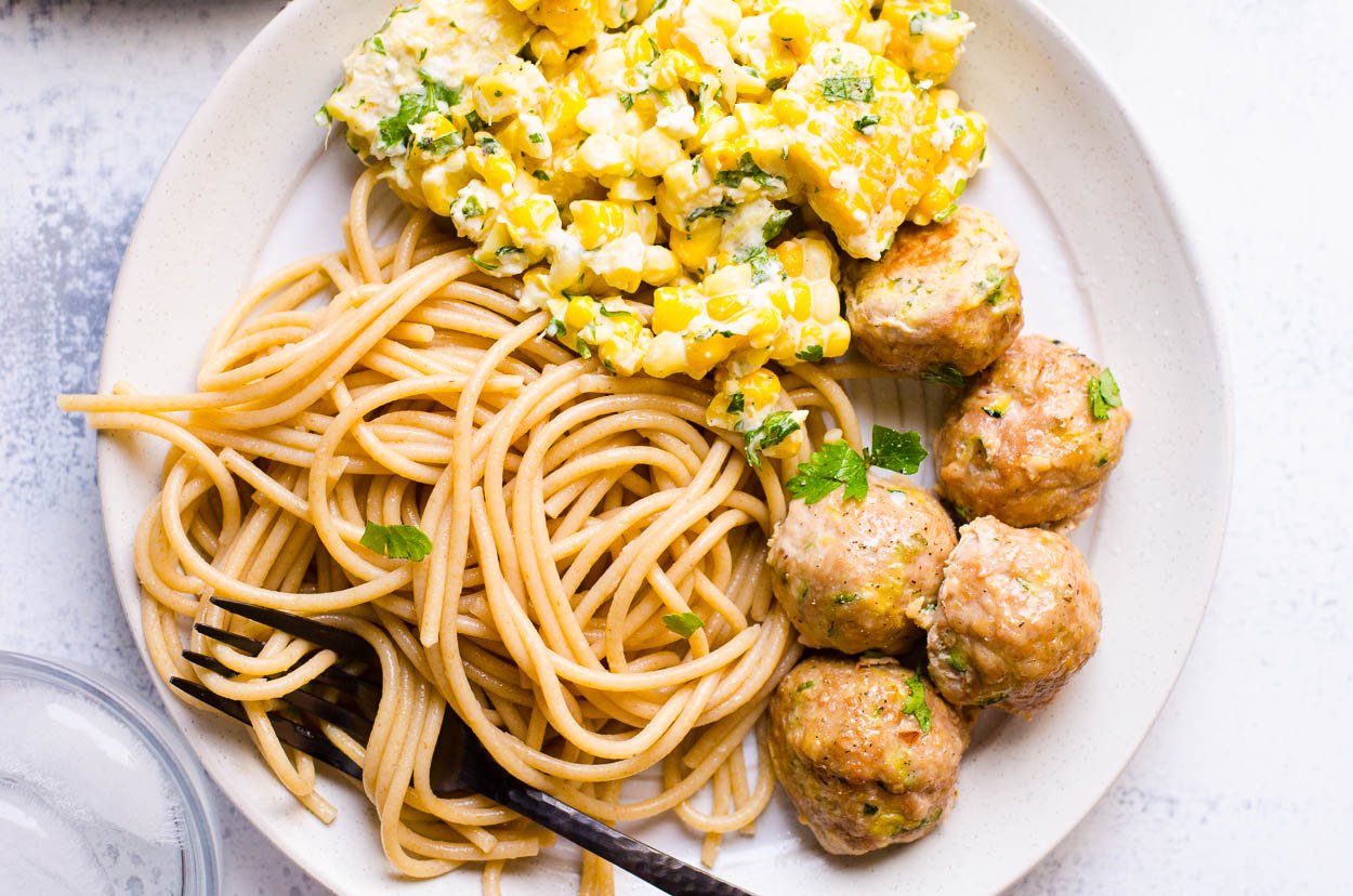 looking at a plate of baked turkey meatballs recipe with noodles and corn with parsley
