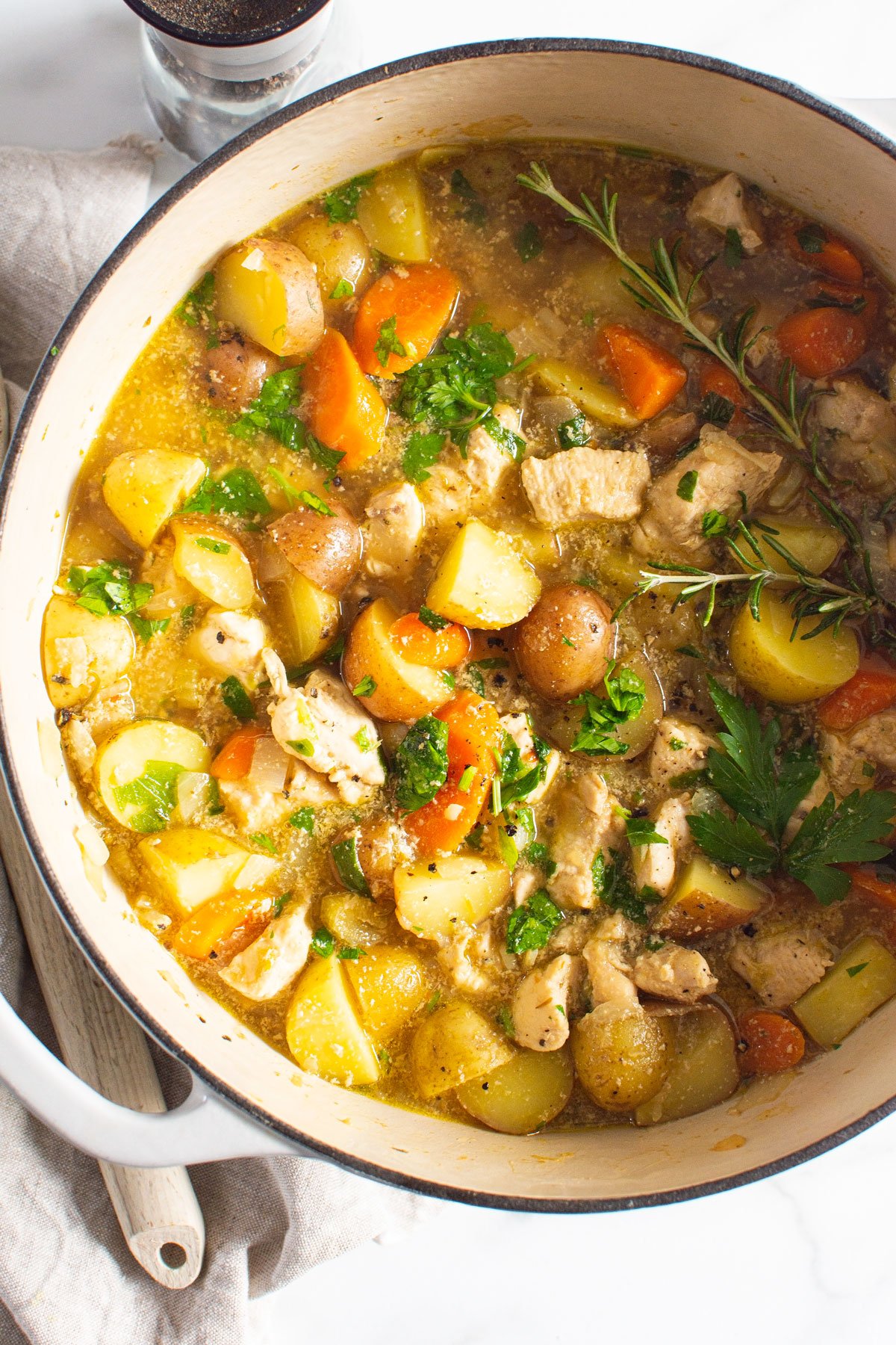 Chicken stew in a pot with linen and spoon.