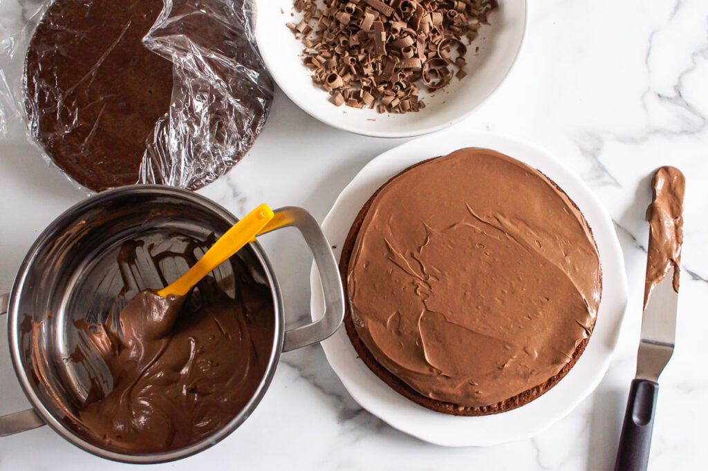 frosting in a pot, cake layers, chocolate shavings