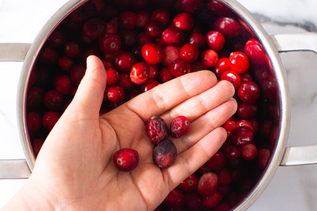 picking out squished cranberries by hand from a pot