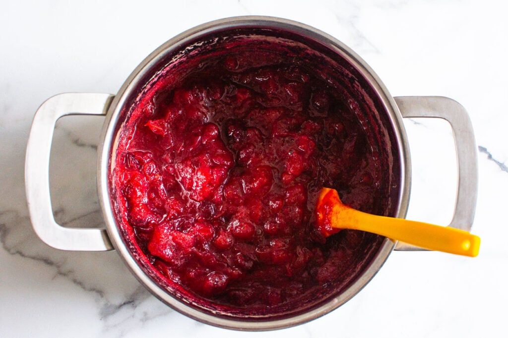 cooked and cooled cranberry sauce in a pot with yellow spatula