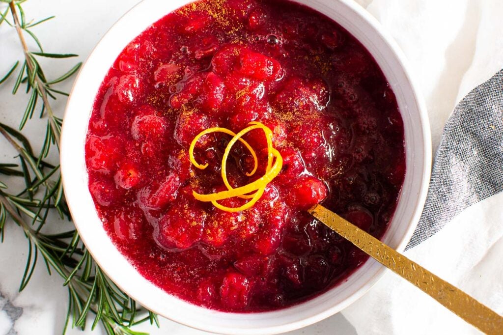 Cranberry sauce in white bowl with orange peels.