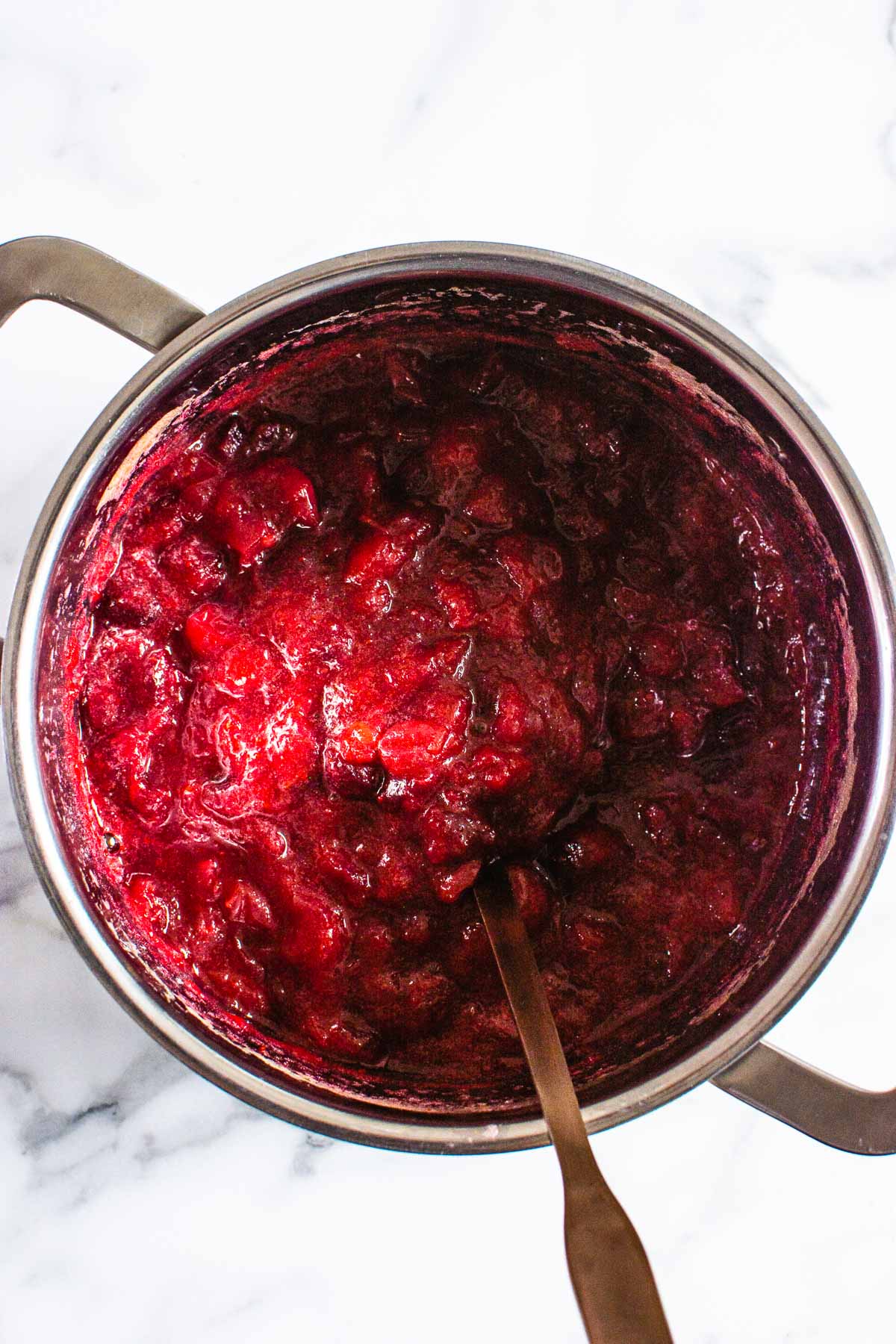 Cranberry sauce in a saucepan with ladle.