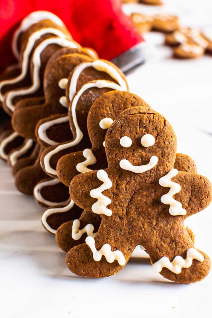 homemade gingerbread men cookies in a row on the counter with a red oven mitt