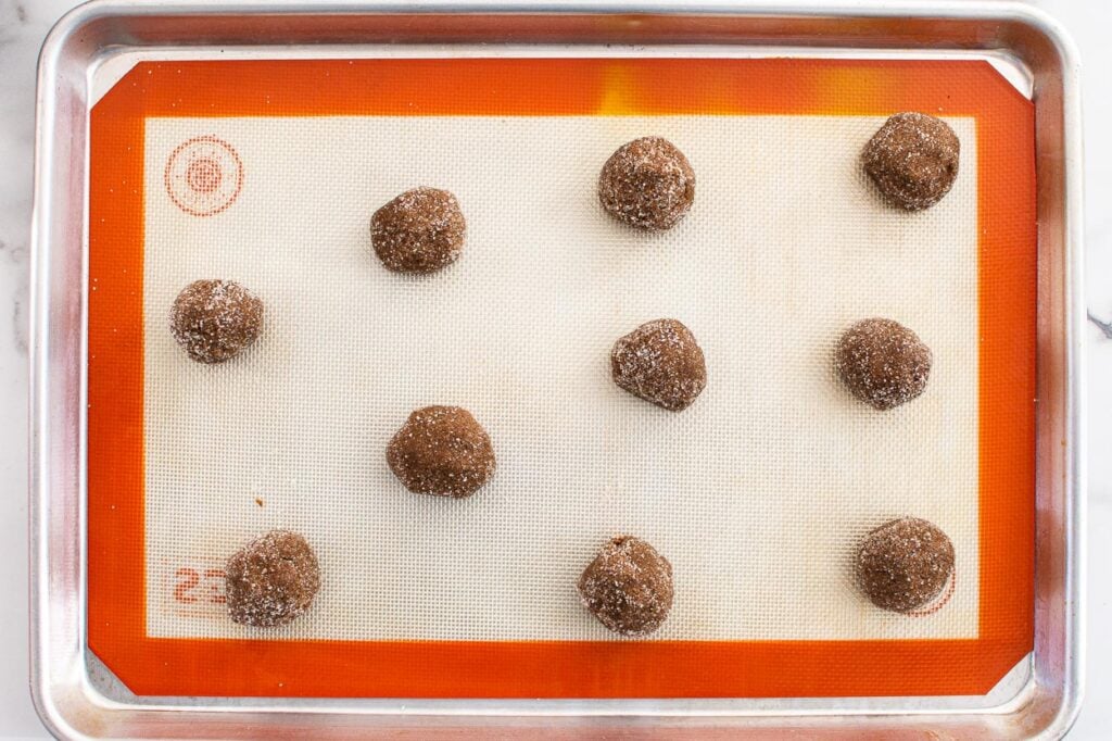 Gingersnap cookie balls on silpat lined baking sheet.
