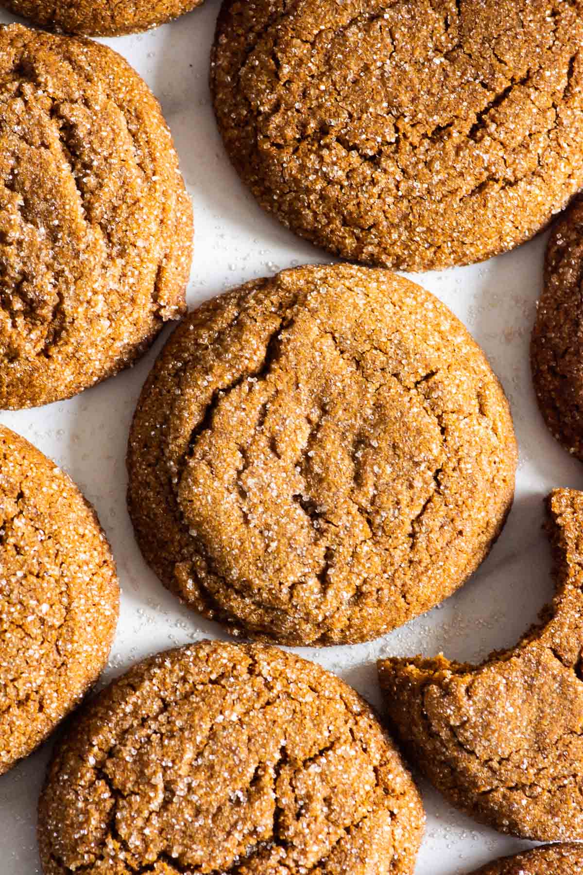 Soft gingersnap cookies on flat surface, with a bite out of one.