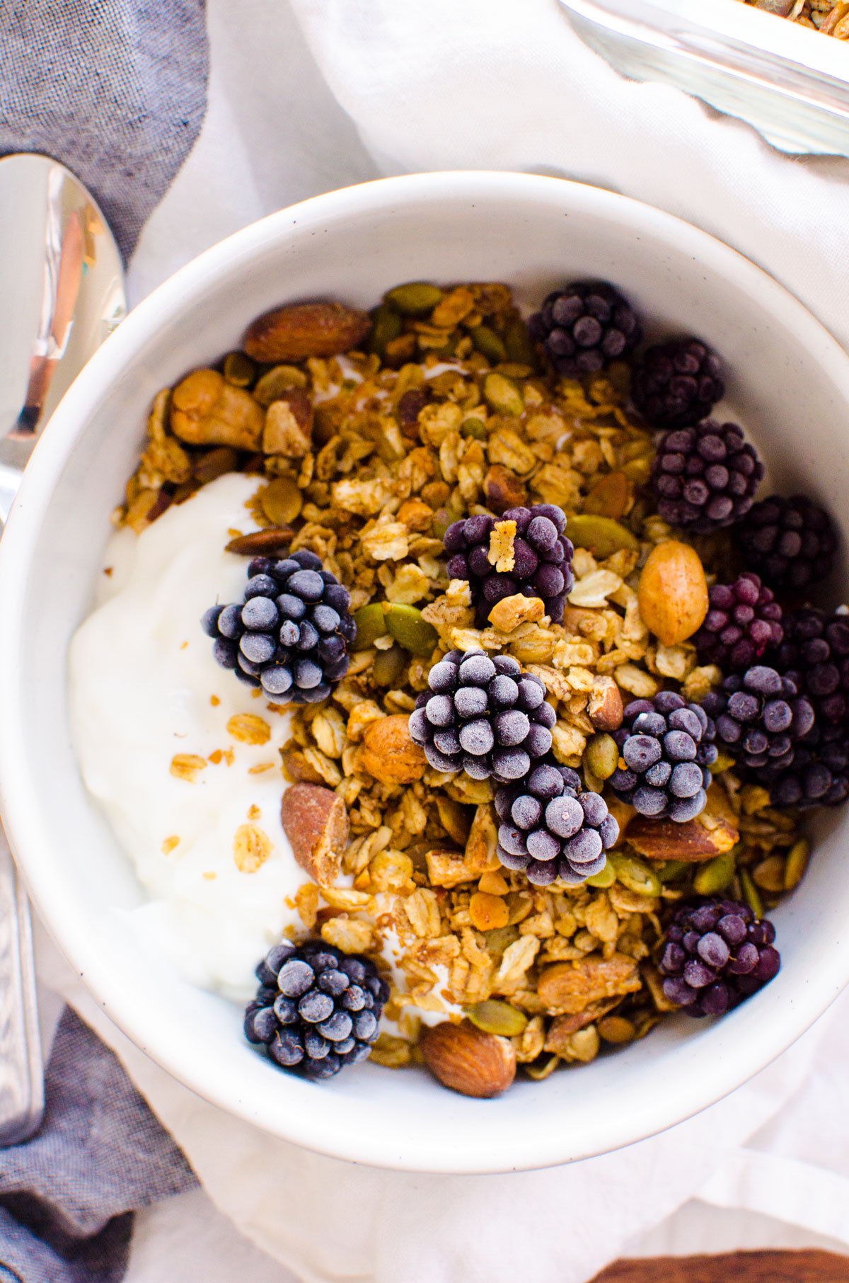 Healthy granola in a bowl with frozen blackberries and yogurt.