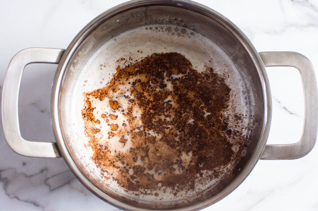 Adding cocoa to milk in saucepan. 