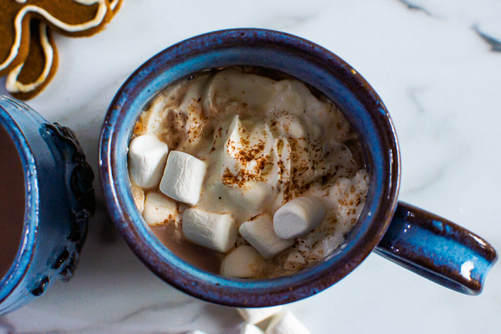 hot cacao in a blue mug with mini marshmallows and whipped cream