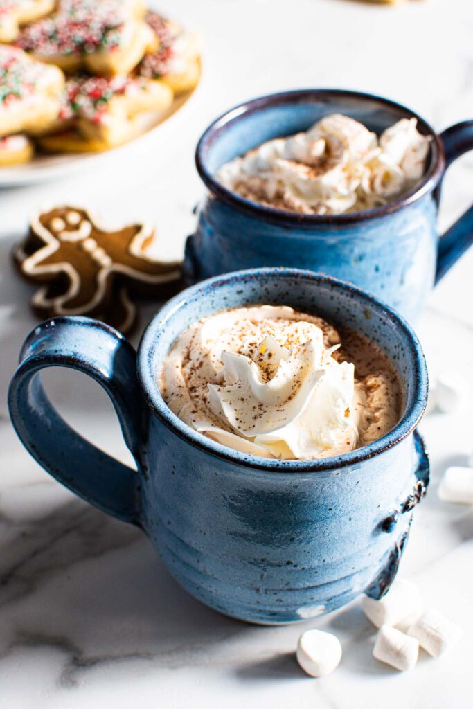 two mugs of healthy hot chocolate with whipped cream and gingerbread cookies