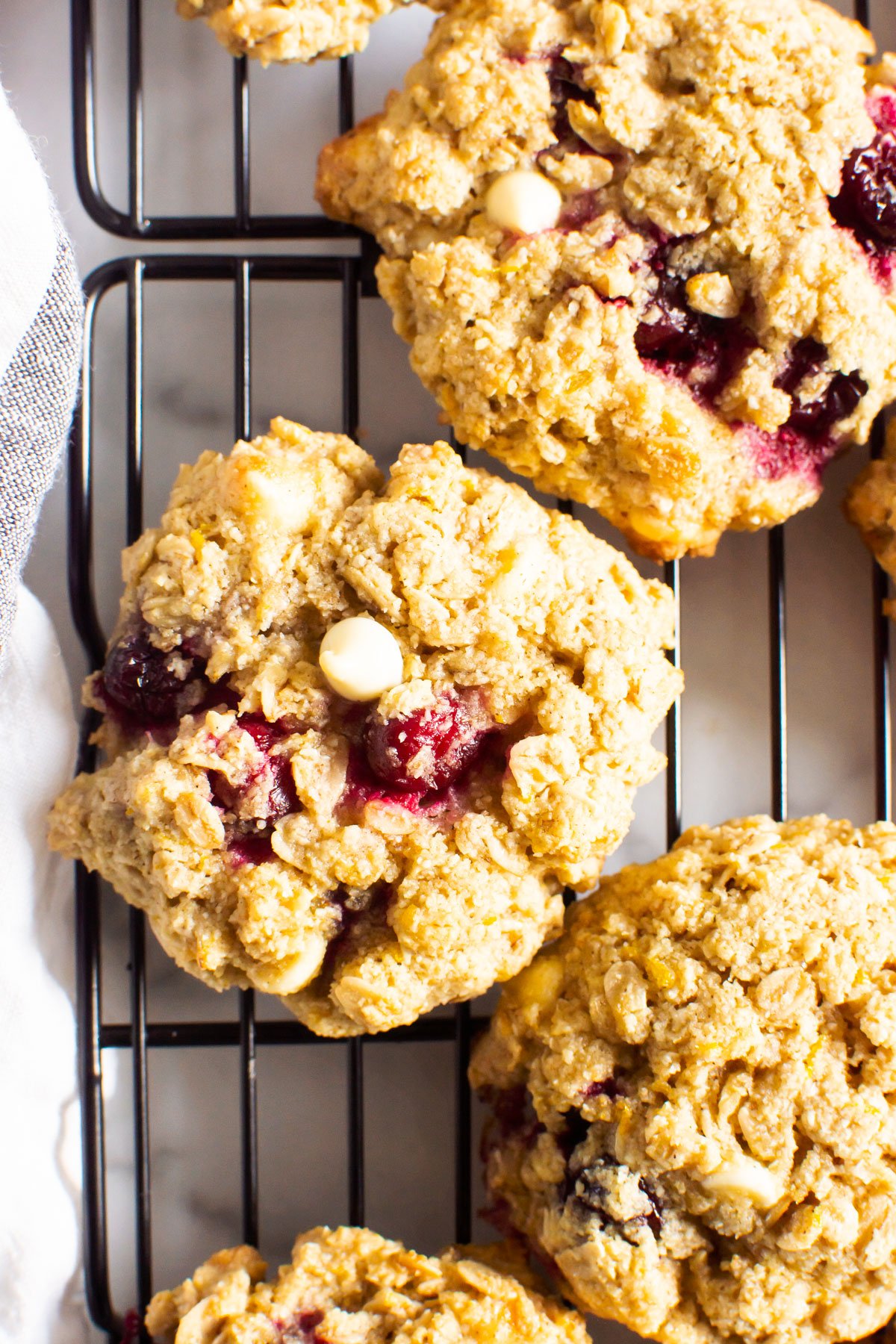 Oatmeal cranberry cookies with white chocolate chips on a cooling rack.