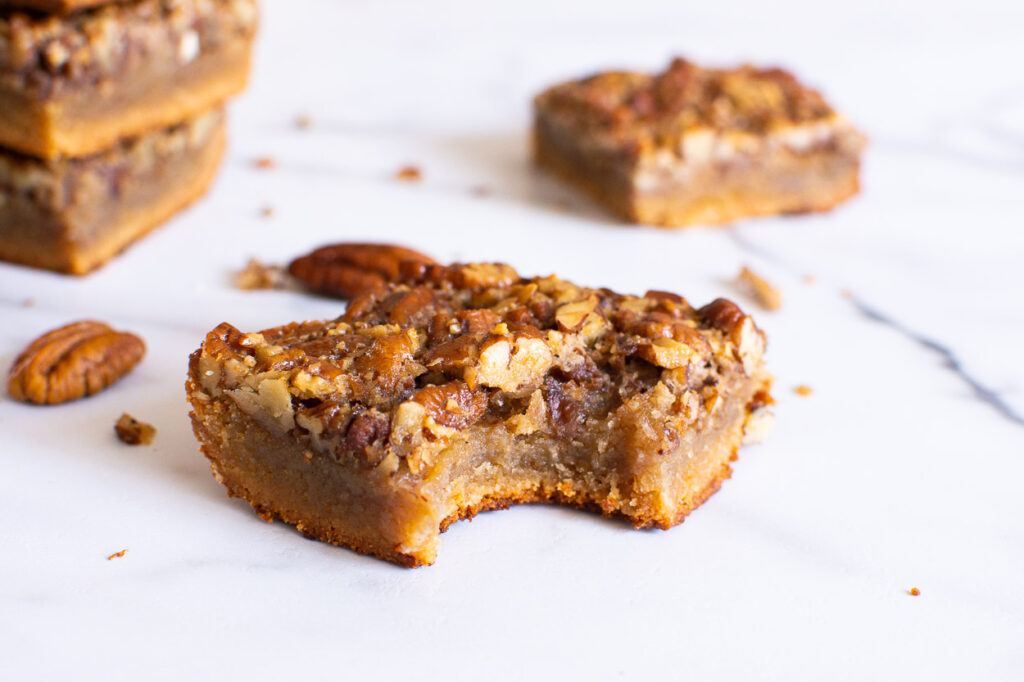 healthy pecan pie bars with a bite taken out of them and a few in background