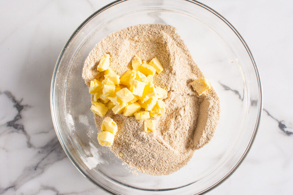 whole wheat flour and cubed butter in glass bowl