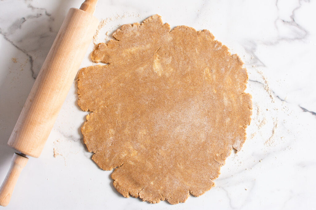 rolled out pie crust on a countertop and rolling pin