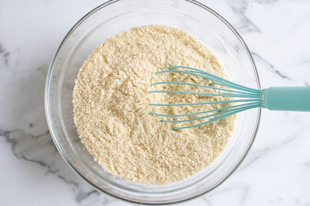 A bowl of almond flour and baking soda being whisked.