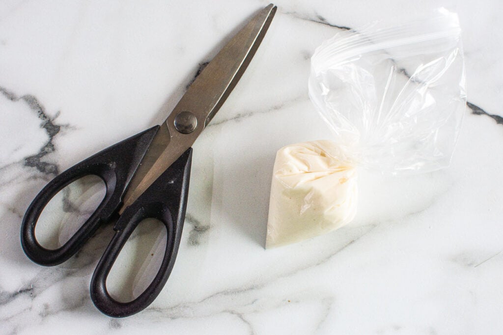 Scissors with a homemade baggie filled with icing. 
