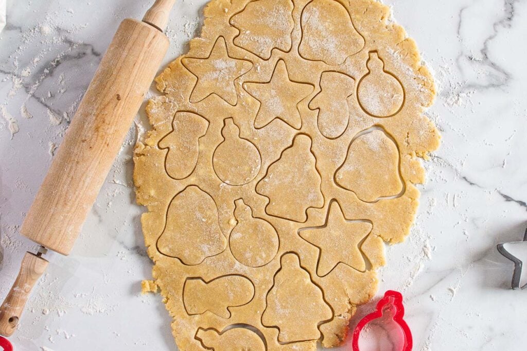 Cutting out healthy sugar cookies with christmas cookie cutters.