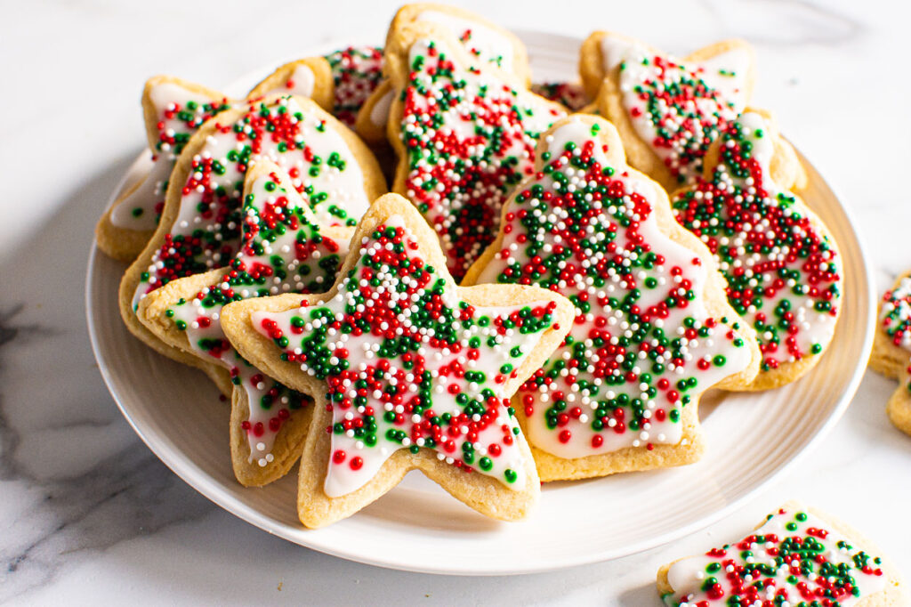 Healthy sugar cookies decorated with icing sugar and sprinkles on plate.
