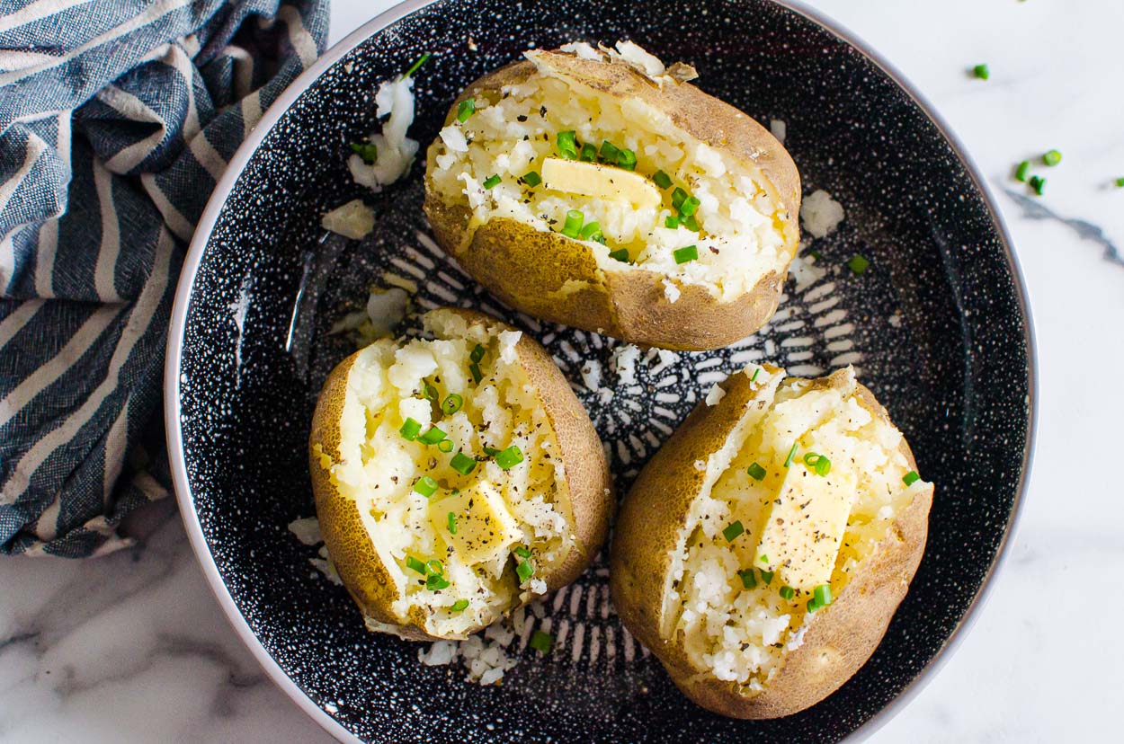 Instant Pot baked potatoes halved and served with butter and chives.