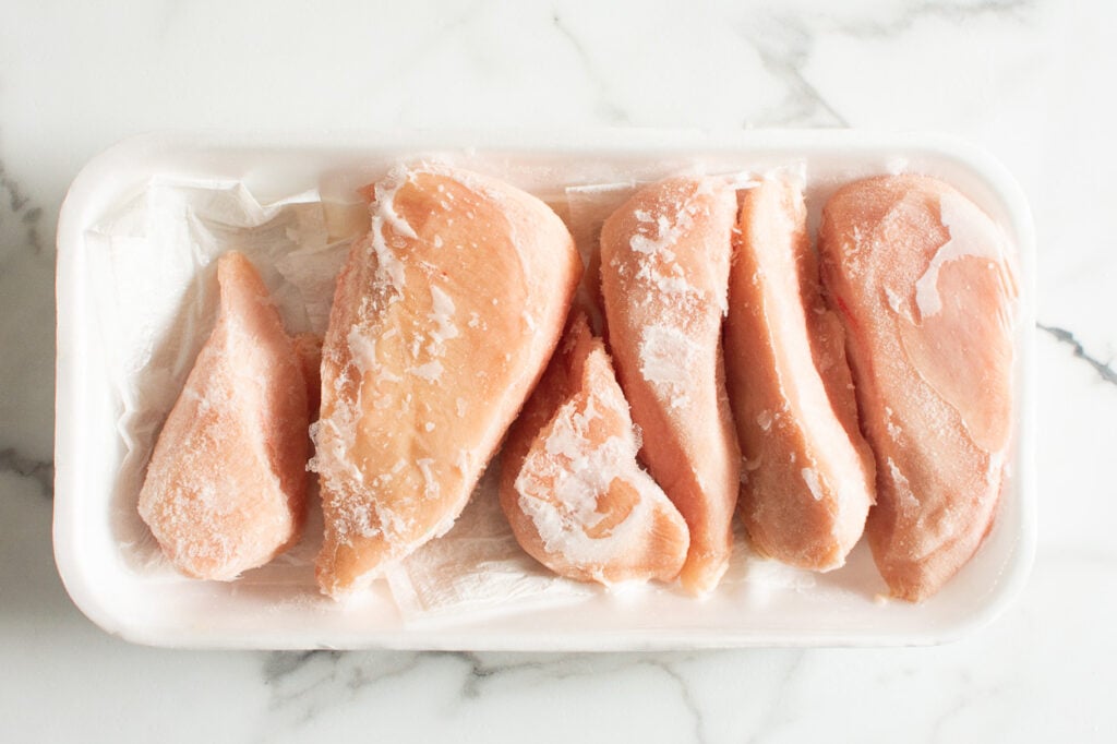 six frozen chicken breasts on a tray