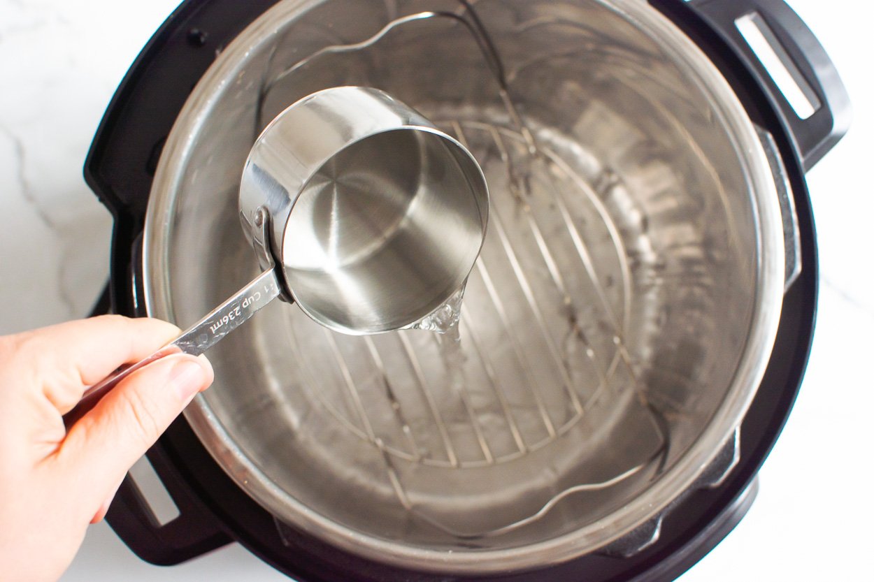 Adding a cup of water to pressure cooker with trivet.