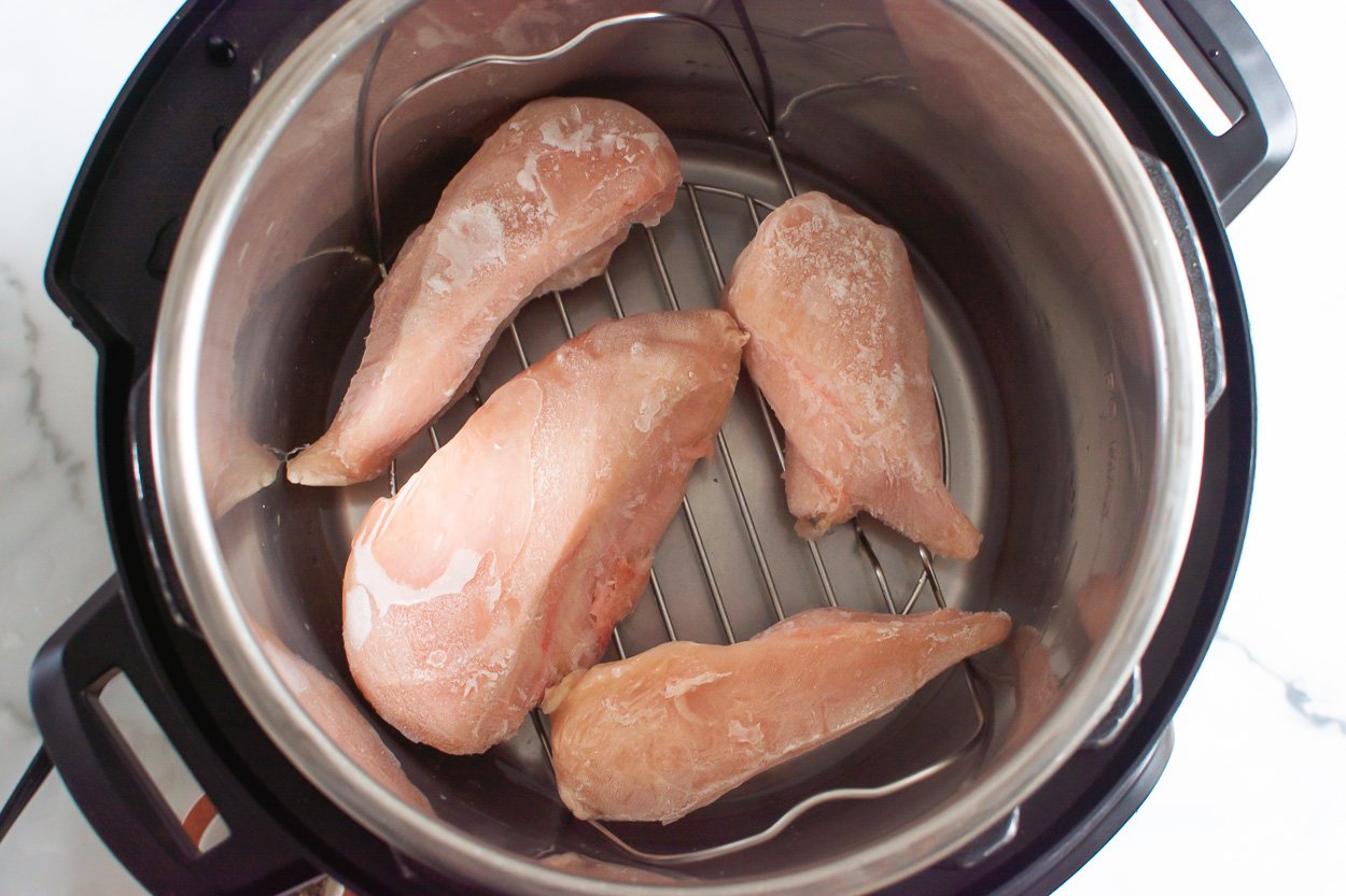 Four frozen chicken breasts in instant pot on a trivet.