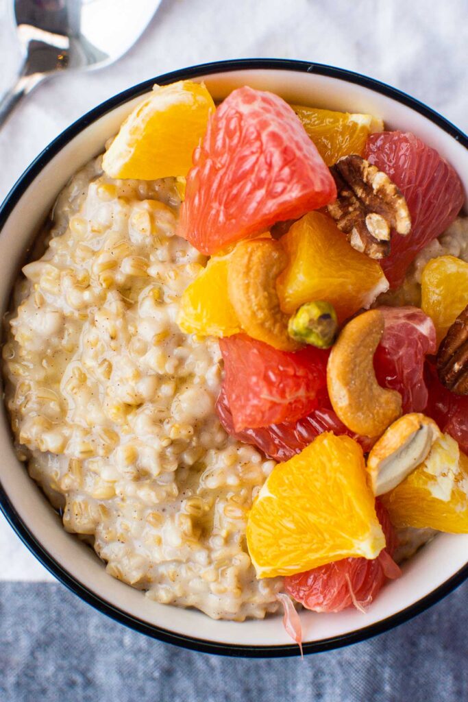 A bowl with Instant Pit steel cut oats topped with chopped citrus fruit and nuts. 