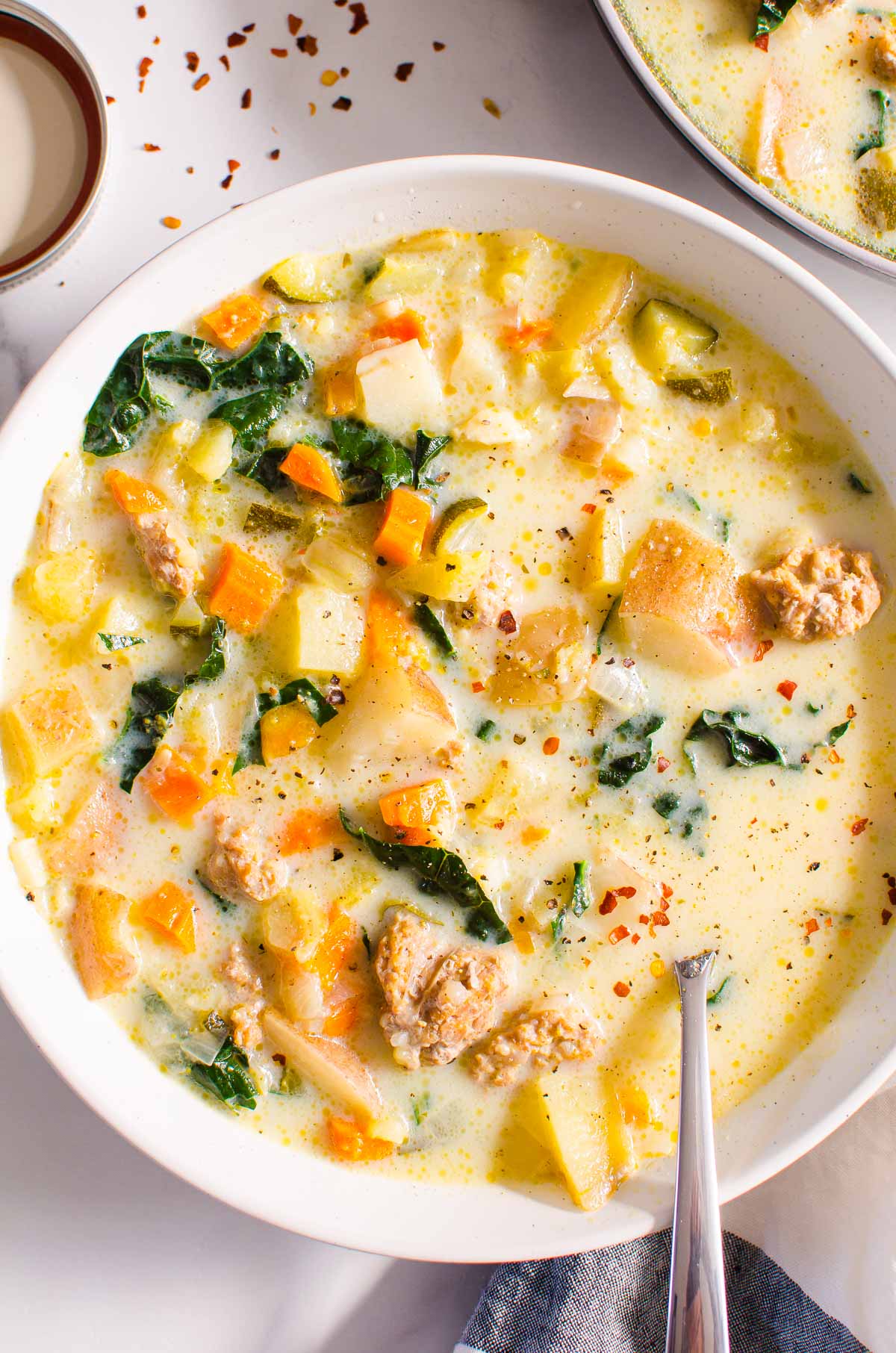 Instant Pot Zuppa Toscana in a bowl with a spoon and napkin with red pepper flakes 