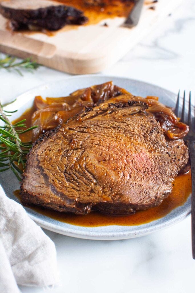 sirloin tip roast recipe with pan juices on a plate ready to eat with napkin and fork