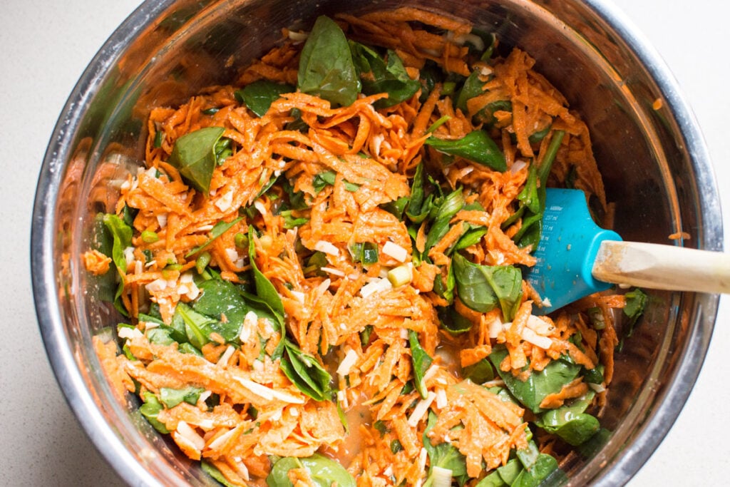 mixed shredded sweet potatoes, spinach, cheese and eggs in metal bowl