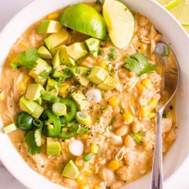 white chicken chili from instant pot with lime avocado and jalapeno garnish in a bowl