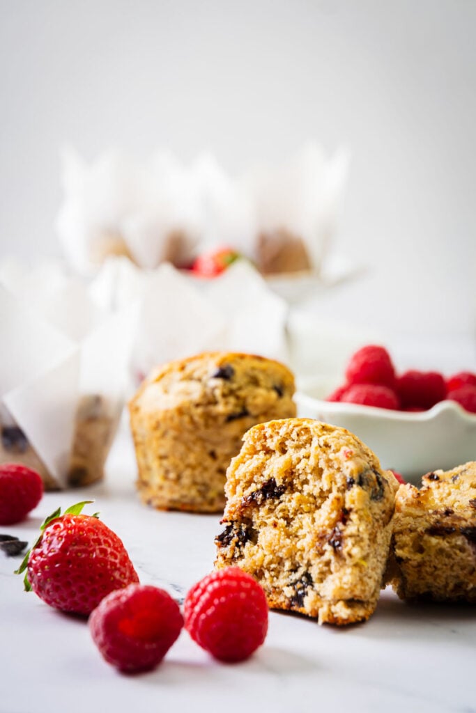 strawberry banana muffins with berries and a muffin in half to show chocolate chips