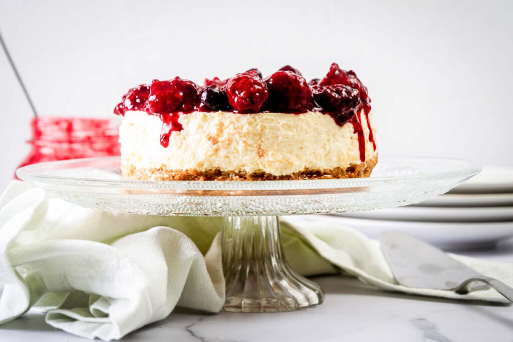 Greek yogurt cheesecake on cake stand with berry compote.