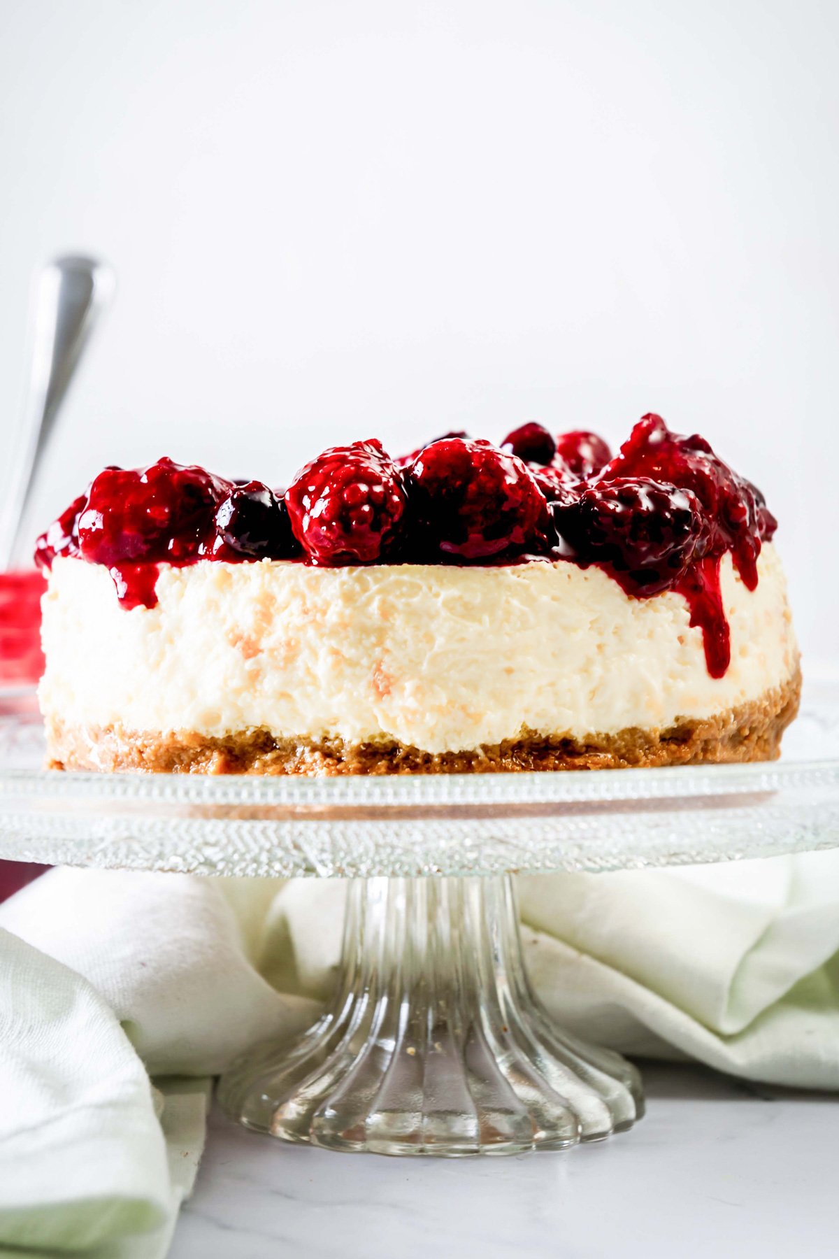 Greek yogurt cheesecake with cherries on cake plate.