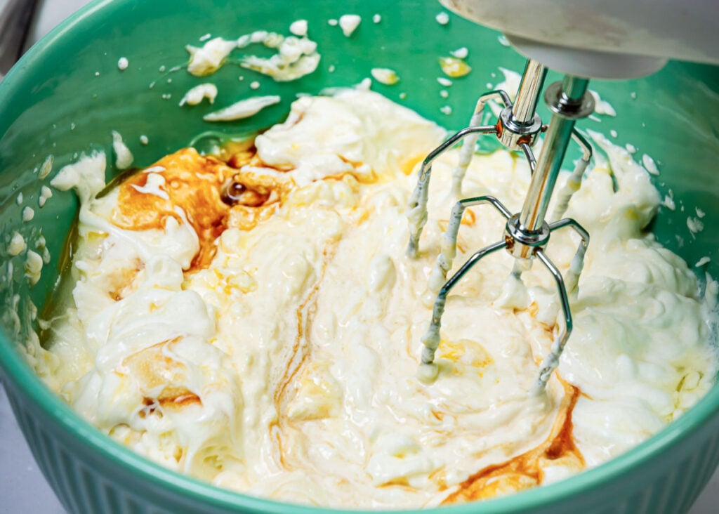 Use electric mixer to whip cream cheese, greek yogurt, eggs and vanilla in a bowl. 