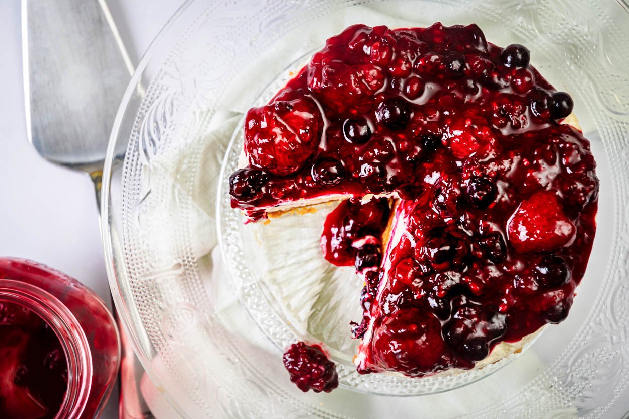 Healthy cheesecake with greek yogurt and cherry compote on a cake platter sliced.