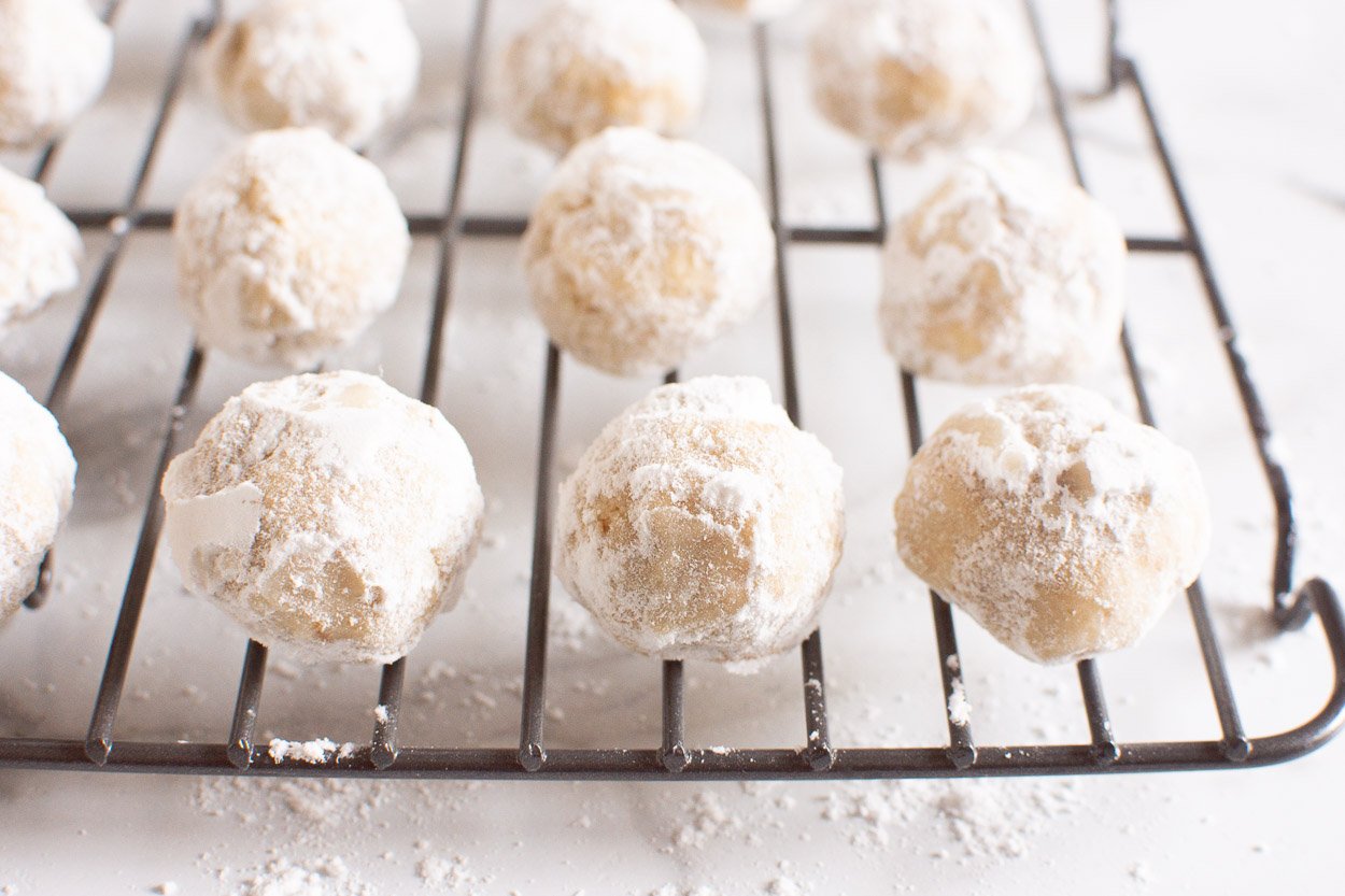 Snowball cookies with almond flour on baking rack.