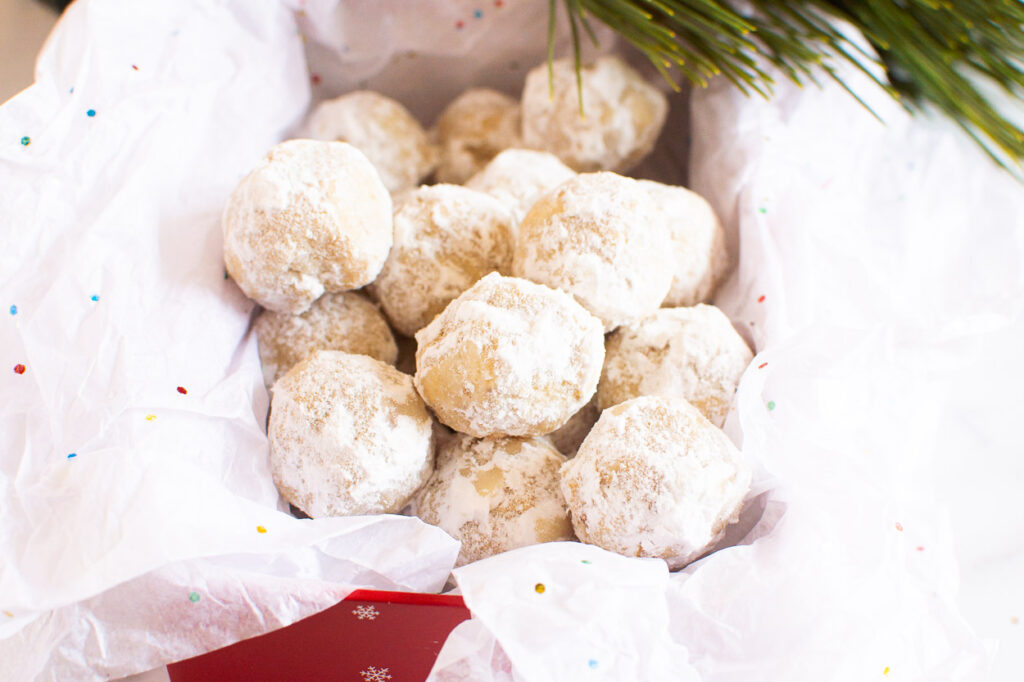 walnut snowball cookies with powdered sugar in a box with tissue paper for gifting