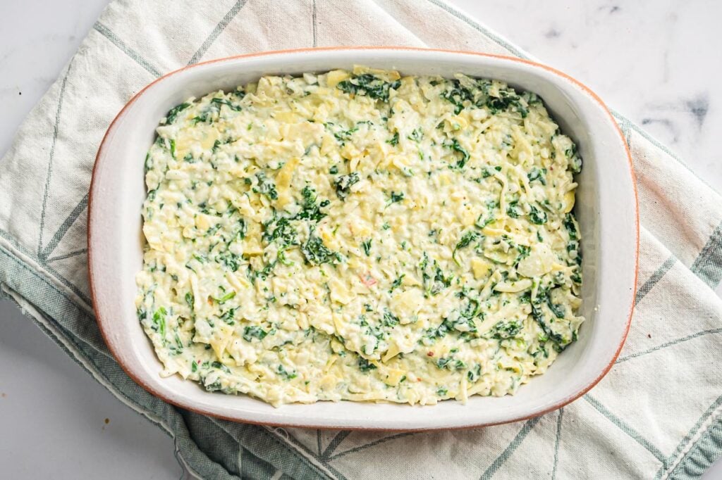 Healthy spinach artichoke dip in baking dish ready to baked.