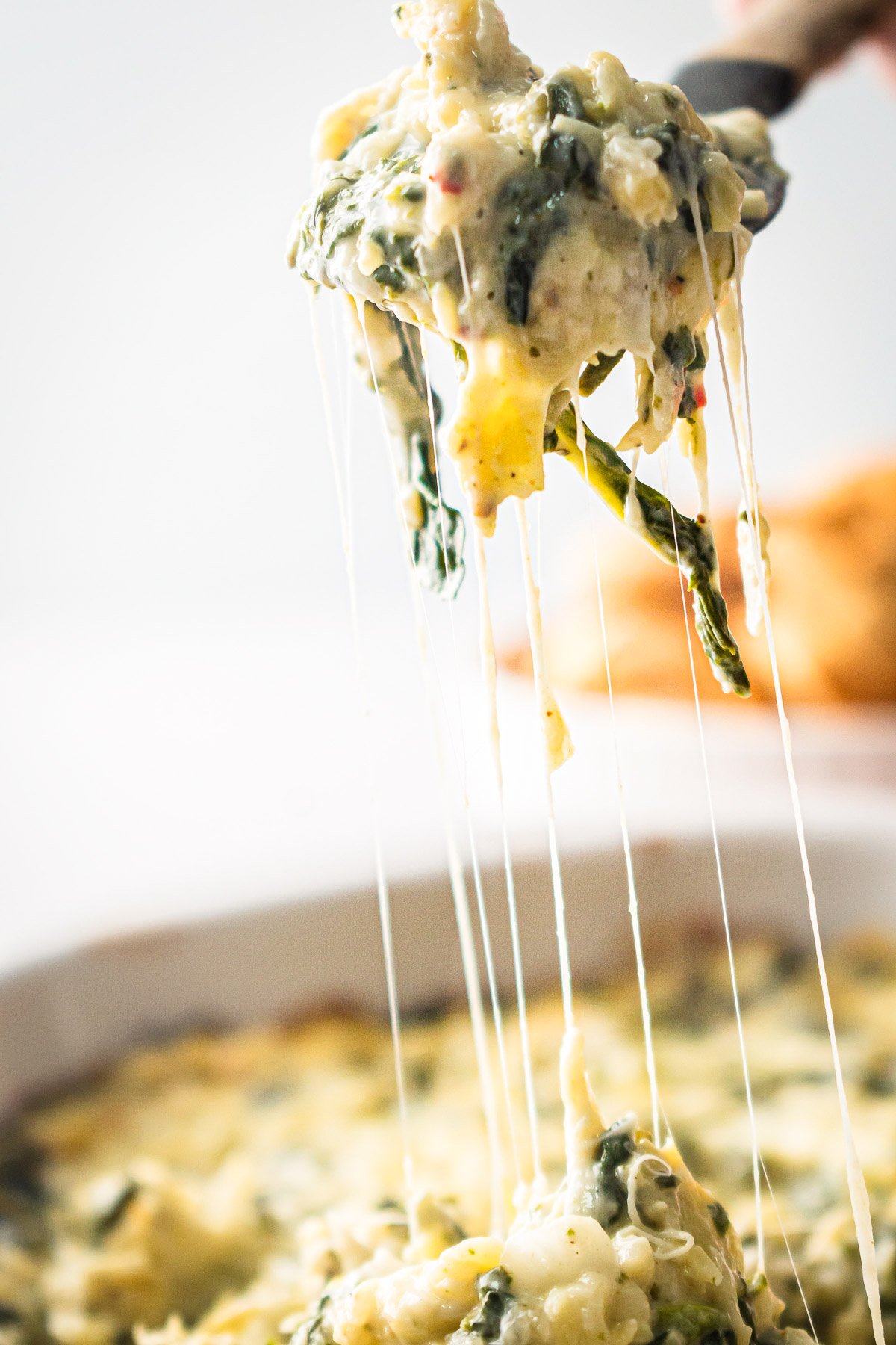 Oven baked healthy spinach artichoke dip on a spoon.