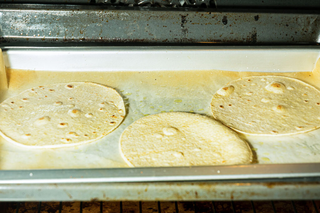 Corn tortillas on pan in oven.