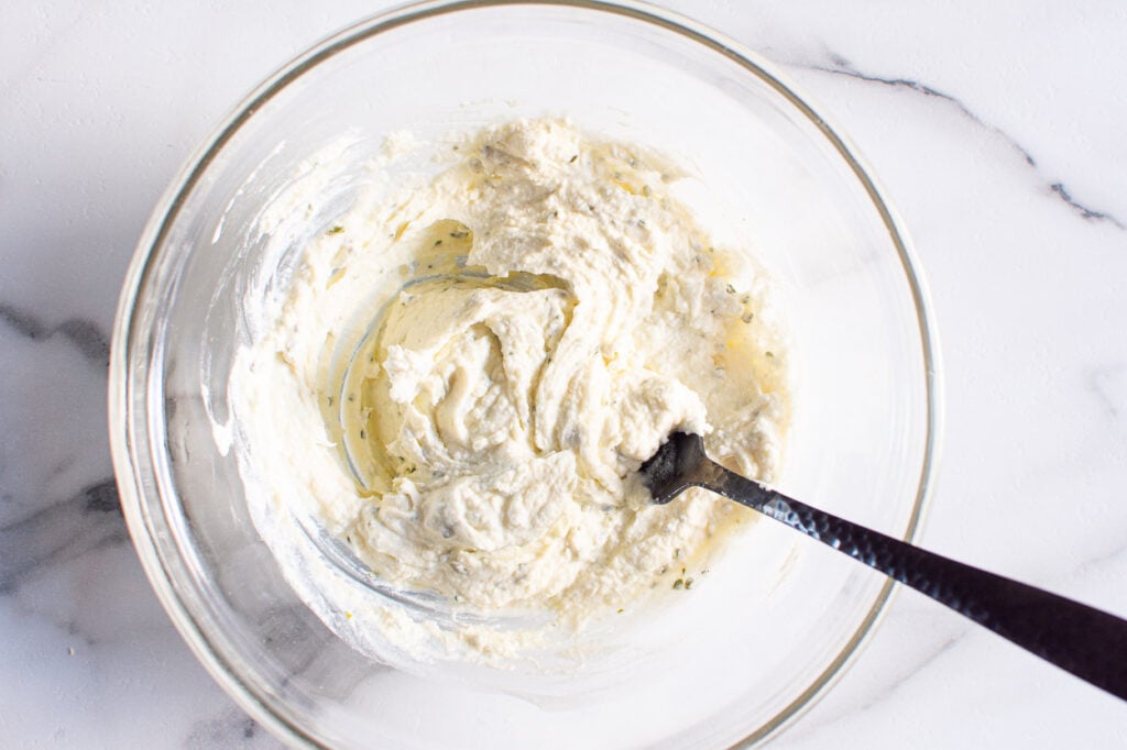 Boursin cheese and water mixed in a bowl.
